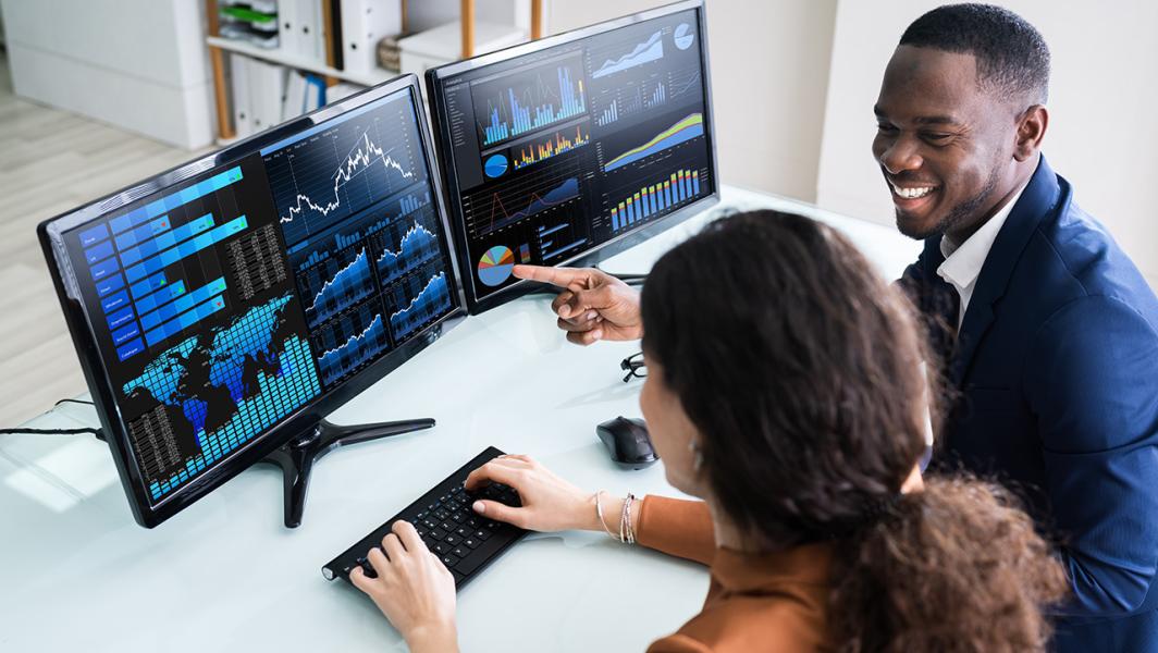Two consultants looking at data together on 2 monitors